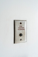 Small fire fighters telephone plug on the white wall in a residence.