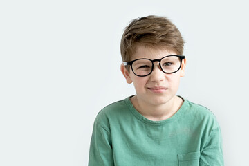 Fototapeta premium Surprised boy in a green T-shirt and glasses pensive scratches his head. Copy space.