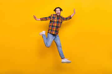 Fototapeta na wymiar Full length photo of joyful brunet millennial guy run wear shirt jeans sneakers isolated on yellow background