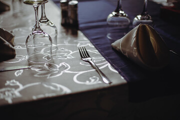 Shallow depth of field (selective focus) image with a restaurant table ready to receive customers. Empty glasses and tableware.