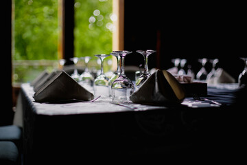 Shallow depth of field (selective focus) image with a restaurant table ready to receive customers. Empty glasses and tableware.