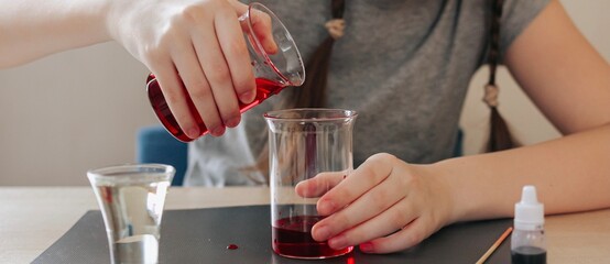 Lava lamp, science experiment with water, food coloring, oil and aspirin doing by school girl. Step by step process of doing homework. Education, back to school, distant banner.