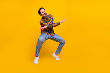 Fototapeta na wymiar Full body photo of lovely brunet young guy dance wear shirt jeans sneakers isolated on yellow background