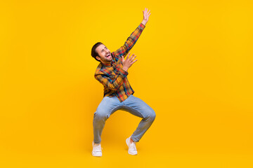 Full length photo of funny brunet millennial guy dance wear shirt jeans sneakers isolated on yellow...