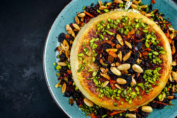 Traditional Persian tahdig jeweled javaher polow bride basmati rice with dried fruits and berries served as top view on a Nordic design plate with copy space left