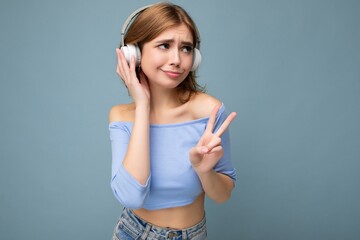Photo of charming sad upset young blonde woman wearing blue crop top isolated on blue background...