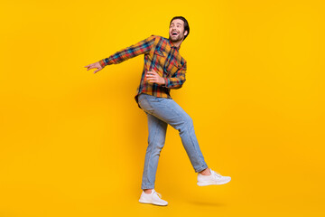 Fototapeta premium Full size photo of joyful brunet millennial guy dance wear shirt jeans sneakers isolated on yellow background