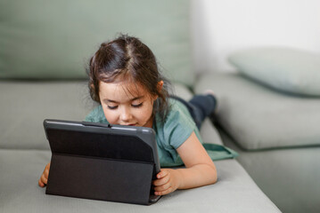 Girl learning through digital tablet at home. Portrait little preschool child video chat with the teacher online. Homeschool, distance learning, video call at home.