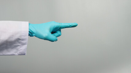 Left Hand point finger and wear blue medical glove with doctor gown isolated on grey background.