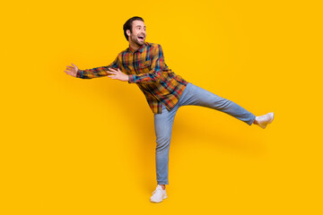 Full body photo of cool brunet young guy dance wear shirt jeans sneakers isolated on yellow background
