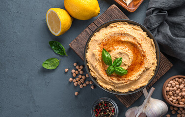 Hummus with paprika, olive oil and basil on a gray-blue background. Top view, copy space.