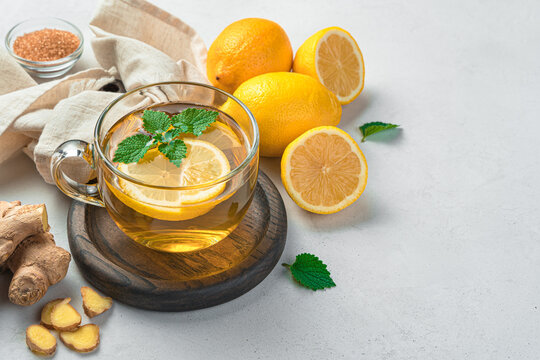 A healthy drink, tea with ginger and lemon on a light background. Side view, space for copying.