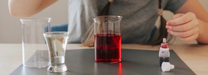 Lava lamp, science experiment with water, food coloring, oil and aspirin doing by school girl. Step by step process of doing homework. Education, back to school, distant banner.