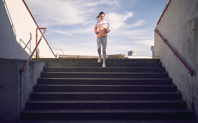 artistic symmetrical image of a caucasian female running down the stairs in sportswear
