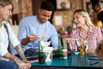 Group of happy employees enjoying eating during a lunch break in the office