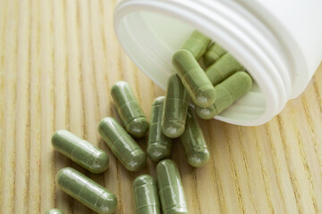 Herbal medicine capsules with bottle on wood table