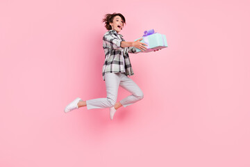 Full size photo of funny young brunette lady jump hold present wear shirt trousers shoes isolated...