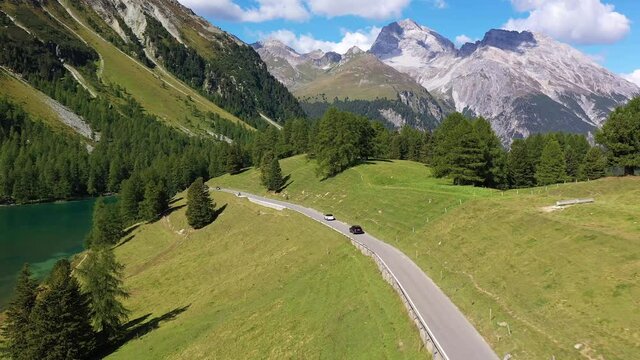 Aerial drone footage of a car driving on the Albula mountain pass road in the alps in Canton Graubunden in Switzerland. Shot with a forward following motion. 