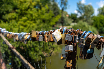 Different coloured locks left on the wire railing of a 100 year old bridge