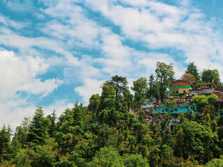 Fototapeta na wymiar Colorful houses in between lush green hills and beautiful clouds in sky