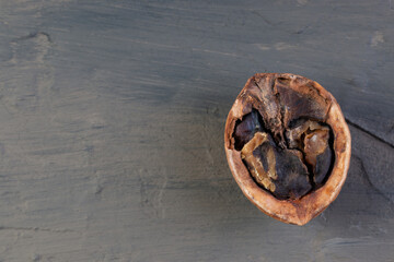 half of a split rotten walnut on a brown concrete or slate background. The concept of a walnut background. top view. A natural product. damaged product
