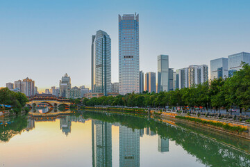 Sunset over the iconic Anshun Bridge in Chengdu, Sichuan, lit up ready for the evening, with modern skyscrapers on the right, overlooking the Jinjiang River with reflections
