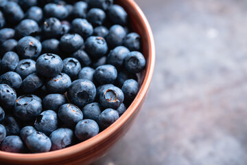 Blueberries in ceramic bowl on rustic wooden background. Selective focus. Shallow depth of field.