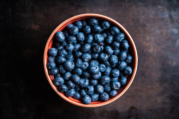 Blueberries in ceramic bowl on rustic wooden background. Selective focus. Shallow depth of field.