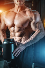 closeup of muscular athlete holding black container with protein whey supplement