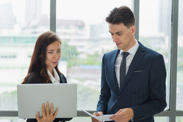 Portrait of adult business man and woman in formal work suit outfit standing and discuss about company investment in modern office room