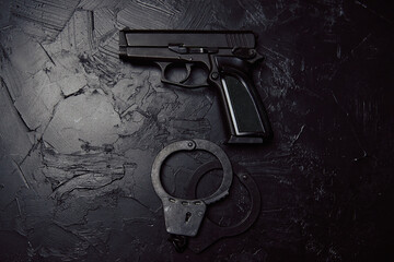 Top view of pistol and handcuffs on dark table. Gun for a law enforcement officer. Ammunition for...