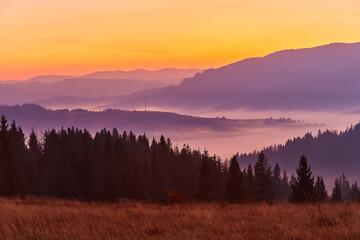 Beautiful autumn sunrise in the mountains. Fog spreads in the lowlands in October