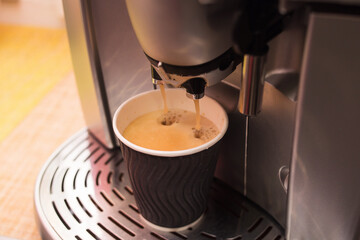 Making coffee in a coffee machine. Cardboard cup
