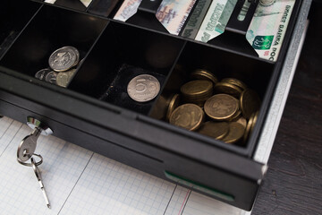 Banknotes and coins of the Russian ruble inside the cash register
