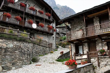 Fototapeta premium Der schöne Ortskern des alten , 1545 m hochgelegene, Bergdorfes Preit in einem Seitental des Val Maira im Piemont mit alten blumengeschmückten Steinhäusern und Steindächern