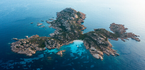 View from above, stunning aerial view of Mortorio island with a beautiful white sand beach and a boat floating on a turquoise water. Sardinia, Italy.
