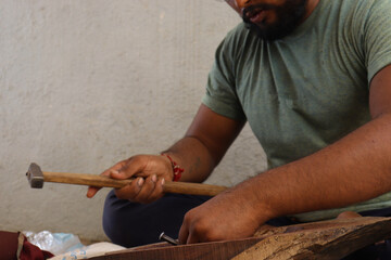 Carpenter is doing woodwork with his hammer and Chisel with Safety glass
