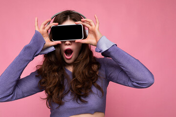 Photo of amazed pretty positive young brunette curly woman wearing purple crop top isolated over...