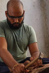 Carpenter is doing woodwork with his hammer and Chisel with Safety glass