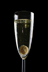 Glass of champagne with bubbles and an olive inside. Isolated on a black background.