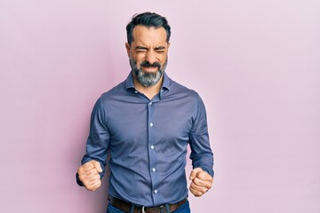 Middle age man with beard and grey hair wearing business clothes very happy and excited doing winner gesture with arms raised, smiling and screaming for success. celebration concept.