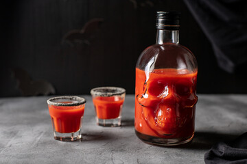 Tomato cocktail in a skull-shaped bottle and glasses. Drink for Halloween party