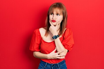 Redhead young woman wearing casual red t shirt thinking worried about a question, concerned and nervous with hand on chin