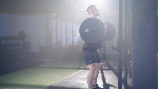Strong man zercher squat with barbell weightlifting in gym haze 4K