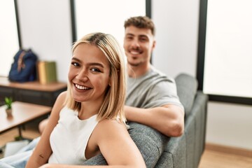 Young caucasian couple smiling happy sitting on the sofa at home.