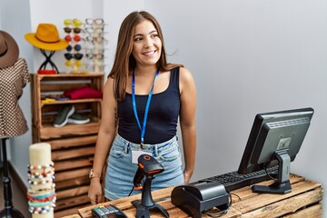 Young brunette woman holding banner with open text at retail shop looking away to side with smile...