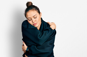 Young hispanic girl wearing sportswear hugging oneself happy and positive, smiling confident. self...