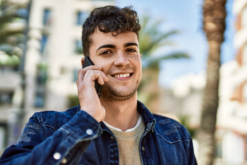 Young hispanic man smiling happy talking on the smartphone at the city