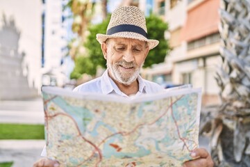 Senior man smiling confident wearing summer hat holding map at street