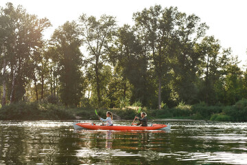Kayak with young couple boating together on a lake surrounded by peaceful summer nature